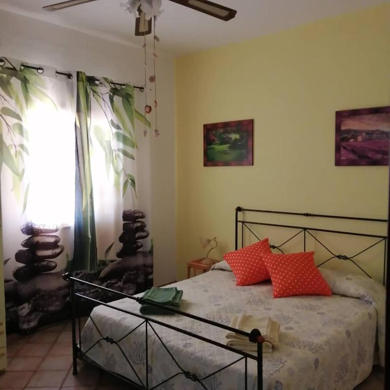 a bedroom with a bed with red pillows and a window at Affittacamere D&D in Porto San Paolo
