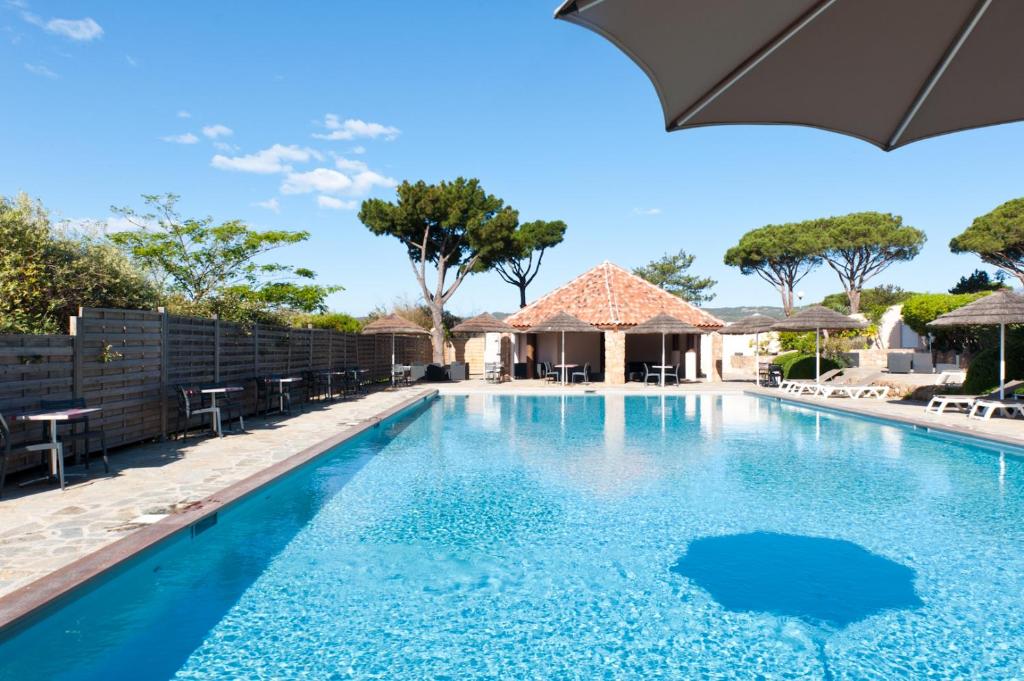 a swimming pool with an umbrella and tables and chairs at Résidence Marina Di Santa Giulia in Porto-Vecchio