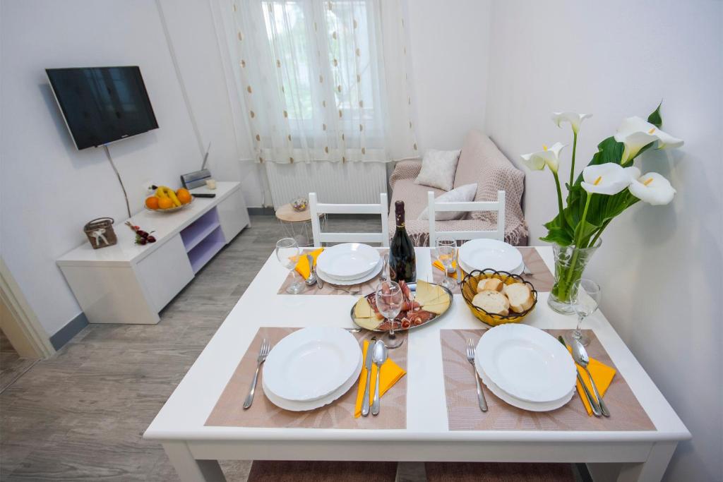 a white table with plates and utensils on it at Apartment Marsela in Šibenik