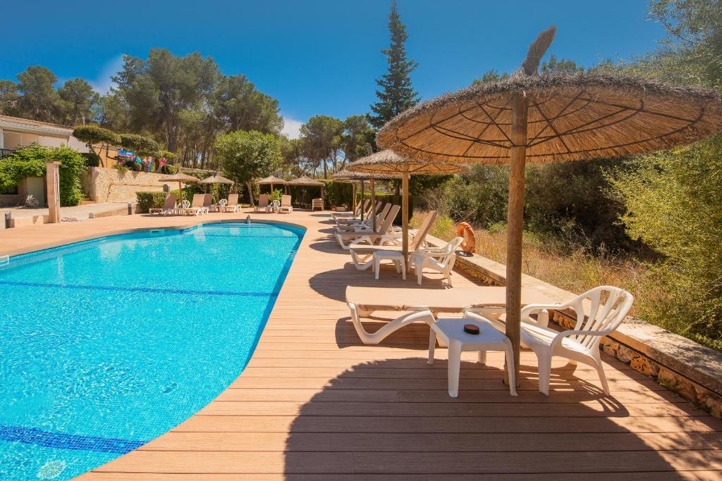 a pool with tables and chairs and an umbrella at Hotel Playa Mondrago in Portopetro