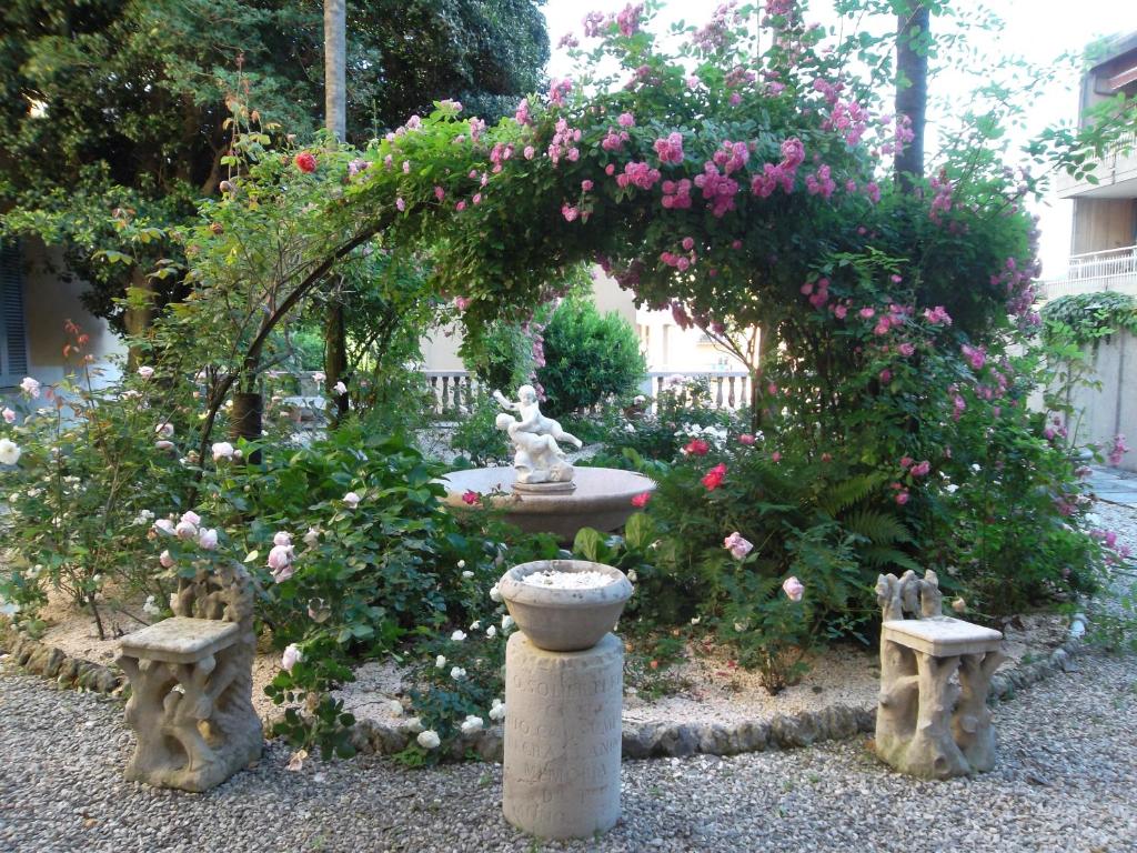 un jardin avec une fontaine et quelques roses roses roses dans l'établissement FeWo Luino Loft, à Luino