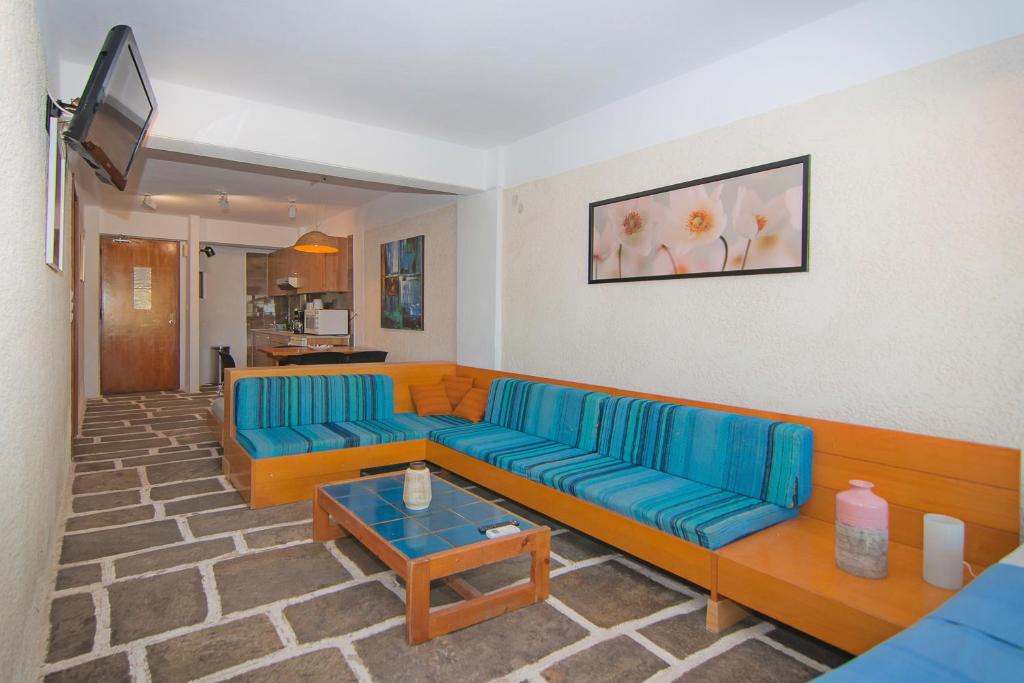 a living room with a blue couch and a table at Apollonia Hotel Apartments in Varkiza