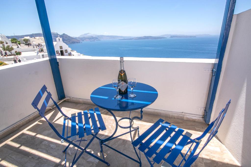 een tafel en stoelen op een balkon met uitzicht op de oceaan bij Stelios Rooms in Oia