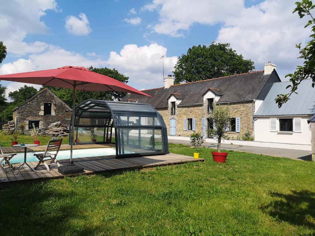 een glazen huis met een rode paraplu en een terras bij LA GALNAIS in Ploërmel