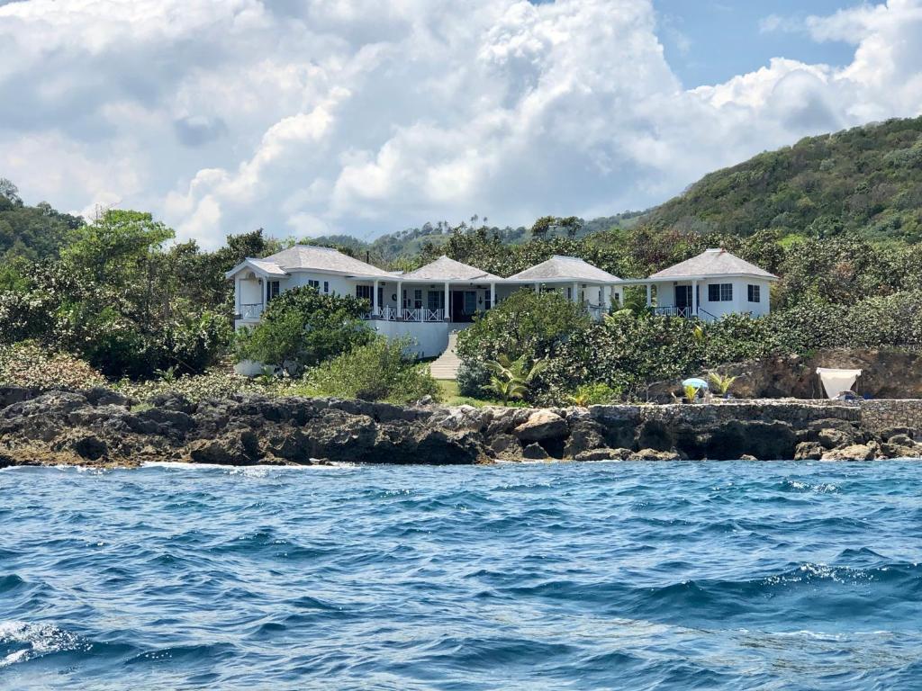 a house on the shore of a body of water at Forever Cottage in Robins Bay