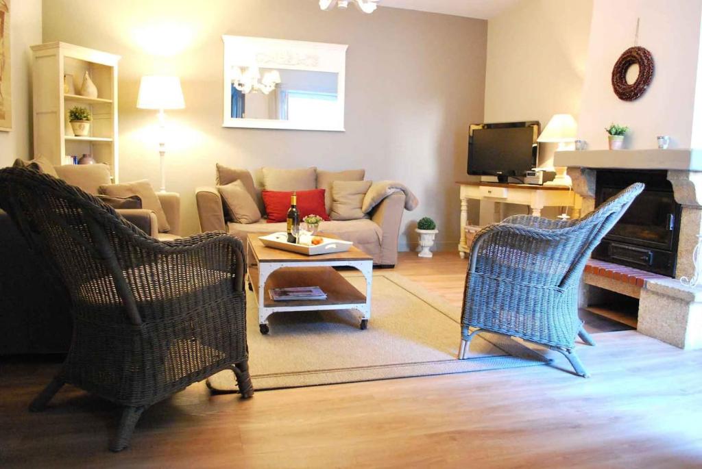 a living room with a couch and chairs and a tv at Location Secrète Sarlat in Sarlat-la-Canéda