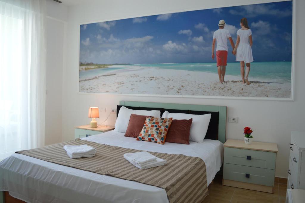een slaapkamer met een groot schilderij van een paar op het strand bij Apartment Bllaca in Shëngjin