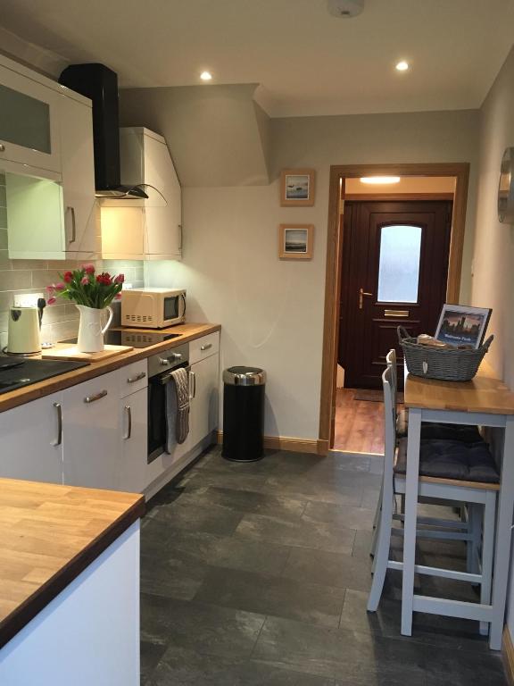 a kitchen with white cabinets and a counter top at Kennedy Terrace; Modern 2 bedroom house, central in Stornoway