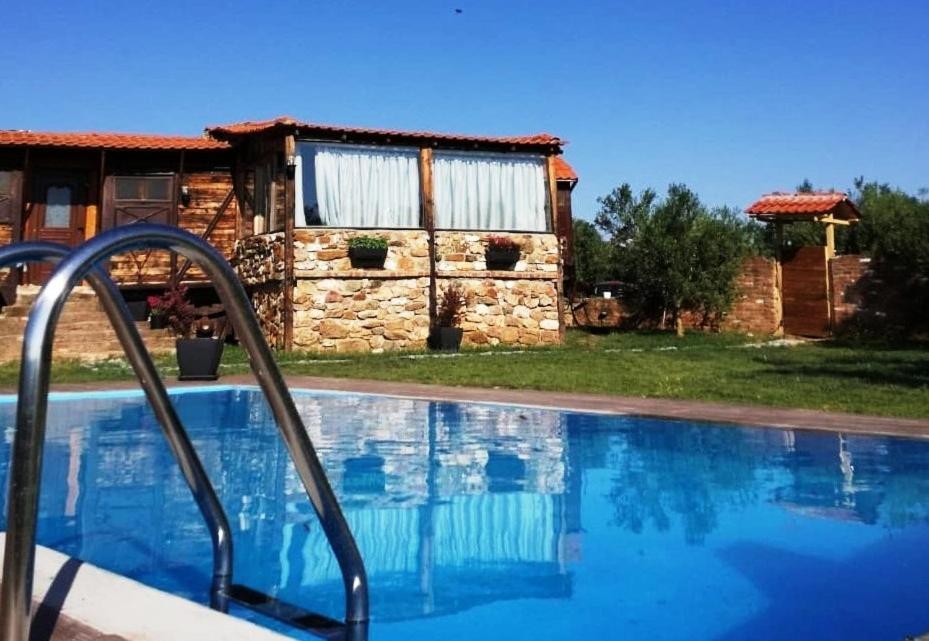 a swimming pool in front of a stone house at Los vagones in Vatopedi