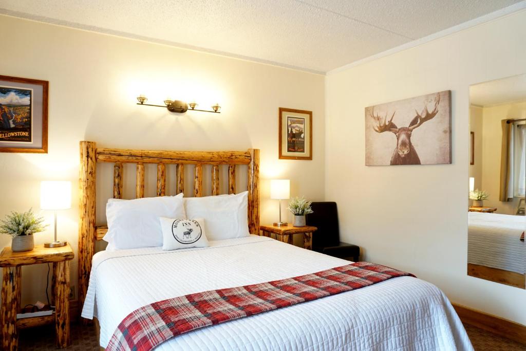 a bedroom with a bed with a white bedspread at Moose Creek Inn in West Yellowstone
