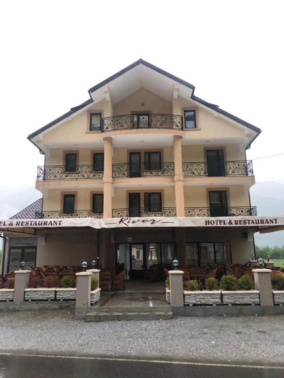 a hotel with a large building in front of it at Hotel River in Gusinje