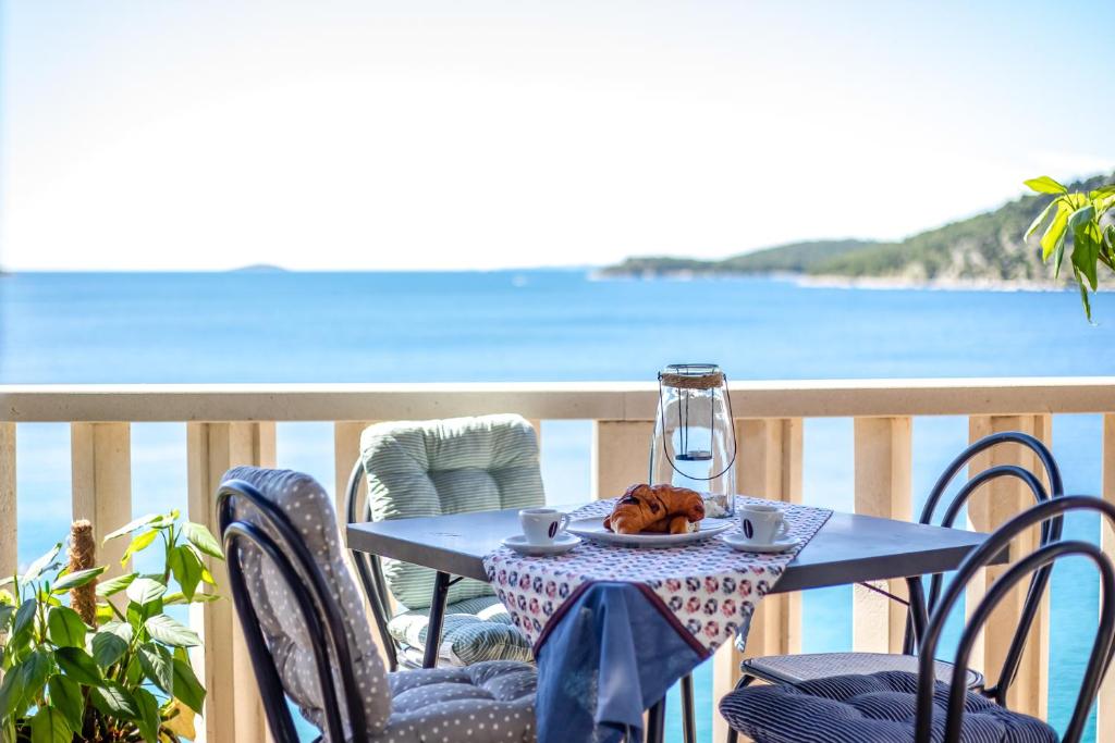 een tafel met een bord eten op een balkon met uitzicht op de oceaan bij Apartments Horizont in Rogoznica
