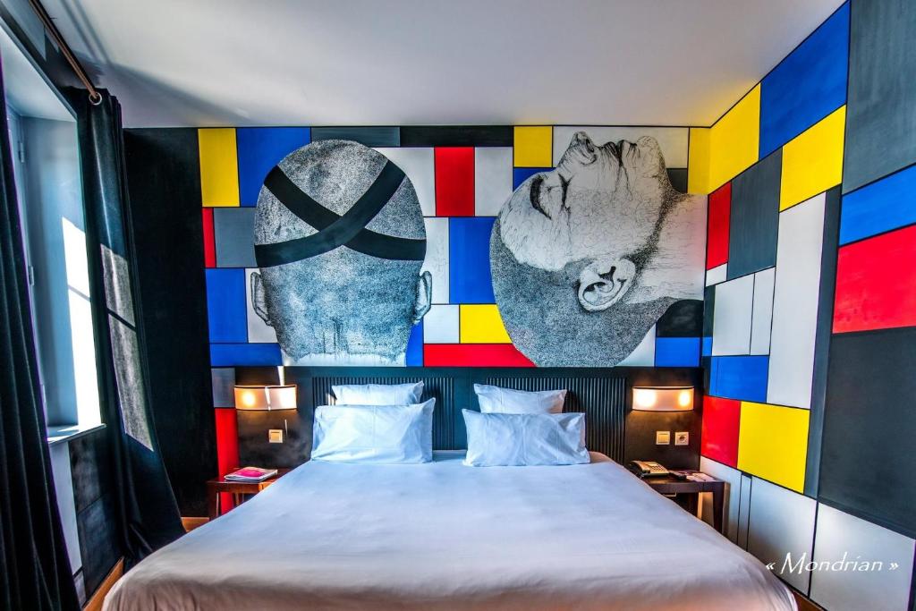 a bedroom with a large bed with a colorful wall at Boutique Hôtel des Beaux Arts in Toulouse