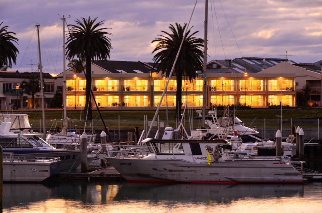 a group of boats docked in a marina with a building at Senator Motor Inn in Gisborne