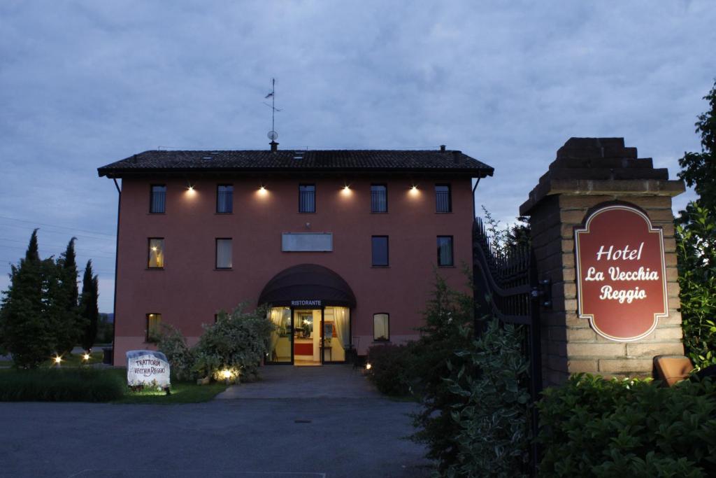 un grand bâtiment avec un panneau devant lui dans l'établissement Hotel La Vecchia Reggio, à Reggio d'Émilie