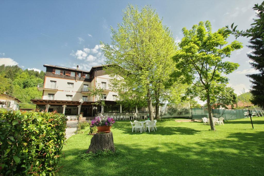 un patio con sillas y árboles blancos y un edificio en Hotel Villa Elia, en Calizzano