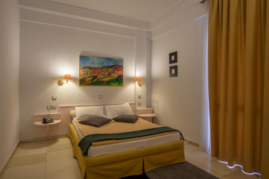 拉里薩的住宿－大都會酒店，卧室配有一张床,墙上挂有绘画作品
