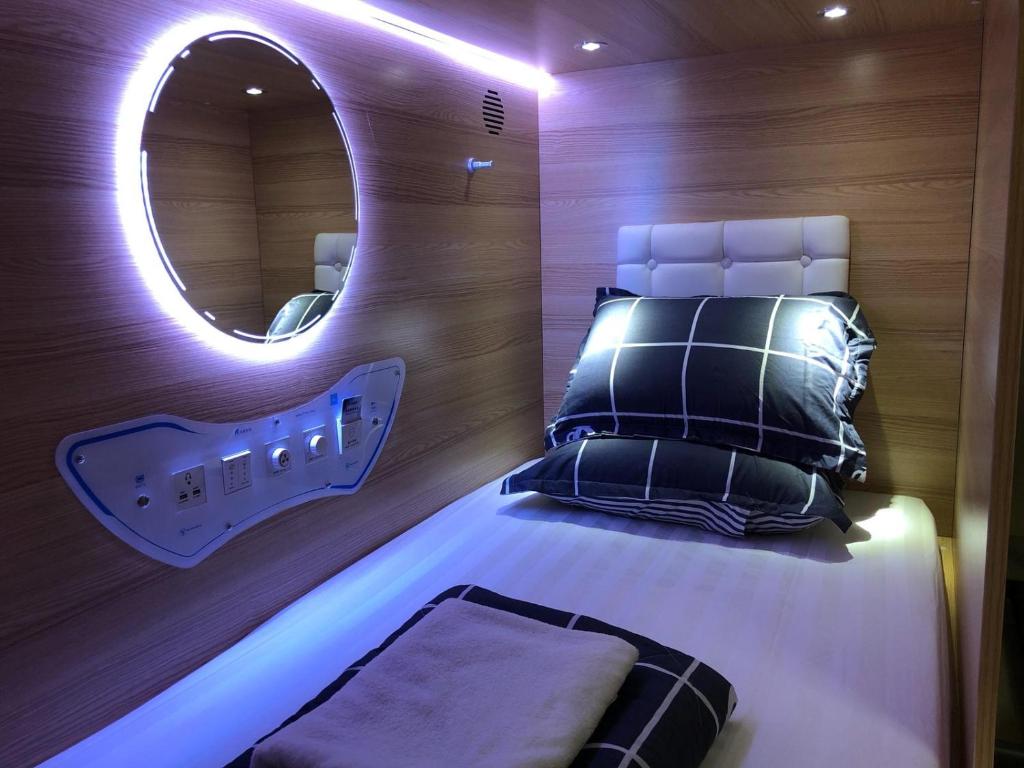a bedroom with a bed with a mirror on the wall at CapsulePod@Aljunied in Singapore