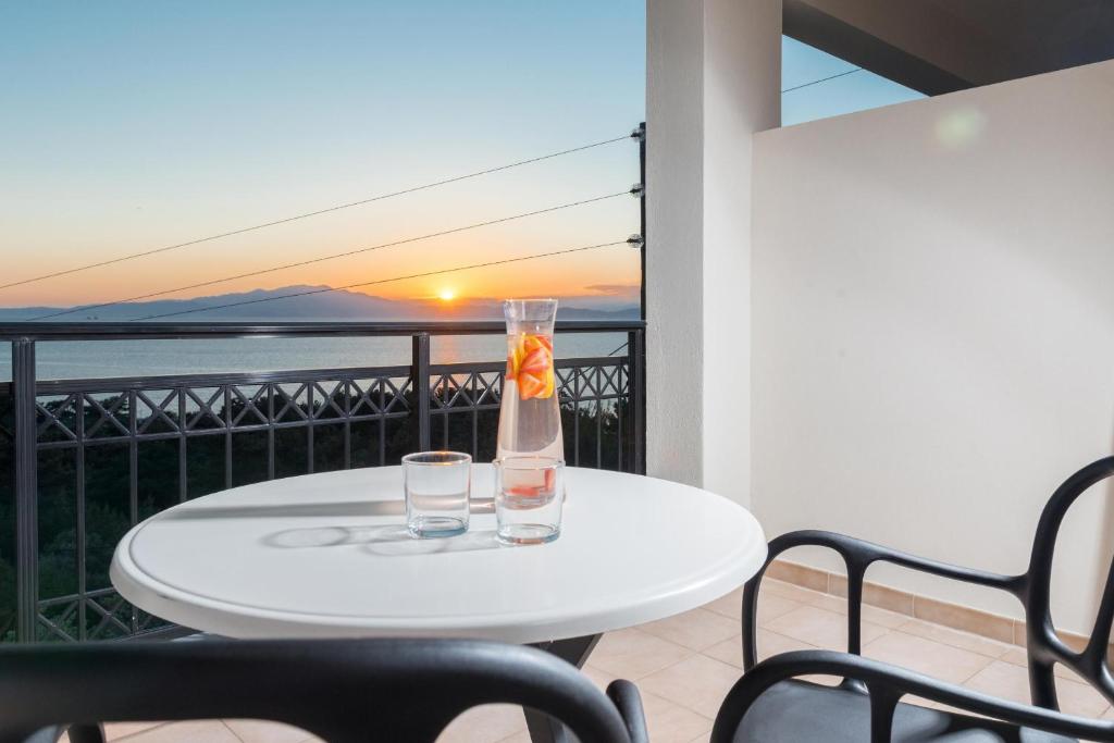 a table with two glasses on a balcony with a view of the ocean at Hotel Villa Natassa in Skala Rachoniou
