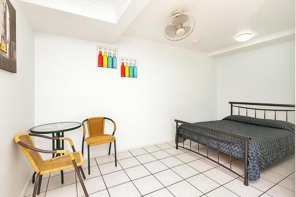 a bedroom with a bed and a table and chairs at Caravella Backpackers in Cairns