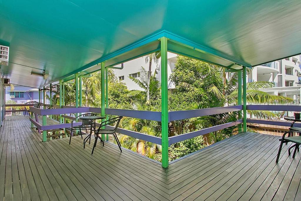 a porch with tables and chairs on a deck at Caravella Backpackers in Cairns