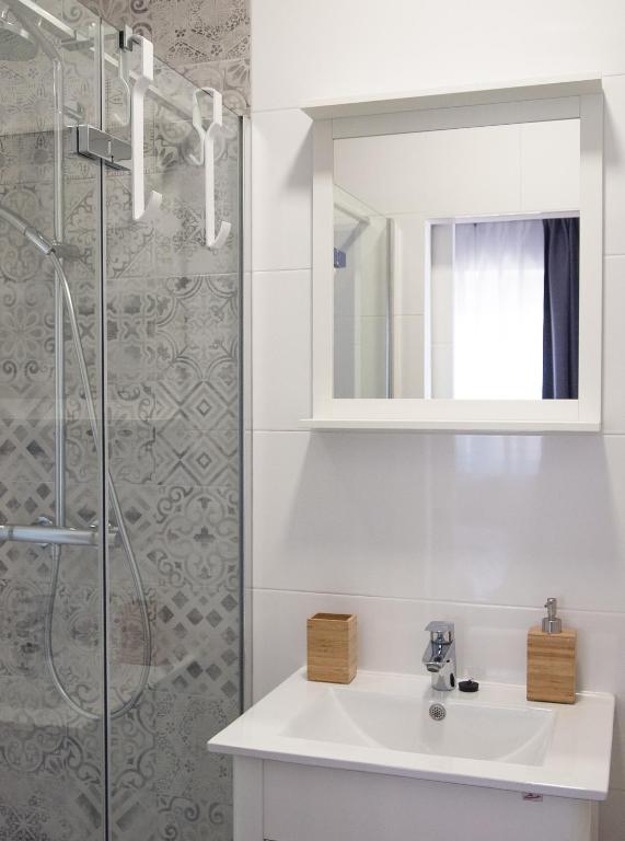 a white bathroom with a sink and a shower at Apartments Nino 1 in Zadar