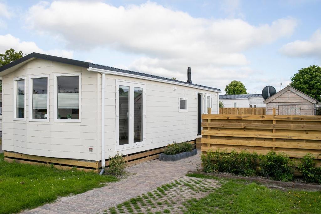 ein weißes winziges Haus mit einem Holzzaun in der Unterkunft Zuiderzee-chalet 22 in Molkwerum