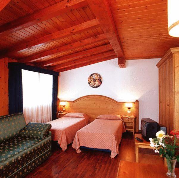 ein Hotelzimmer mit 2 Betten und einem Sofa in der Unterkunft Albergo Scarpone in Forni Avoltri