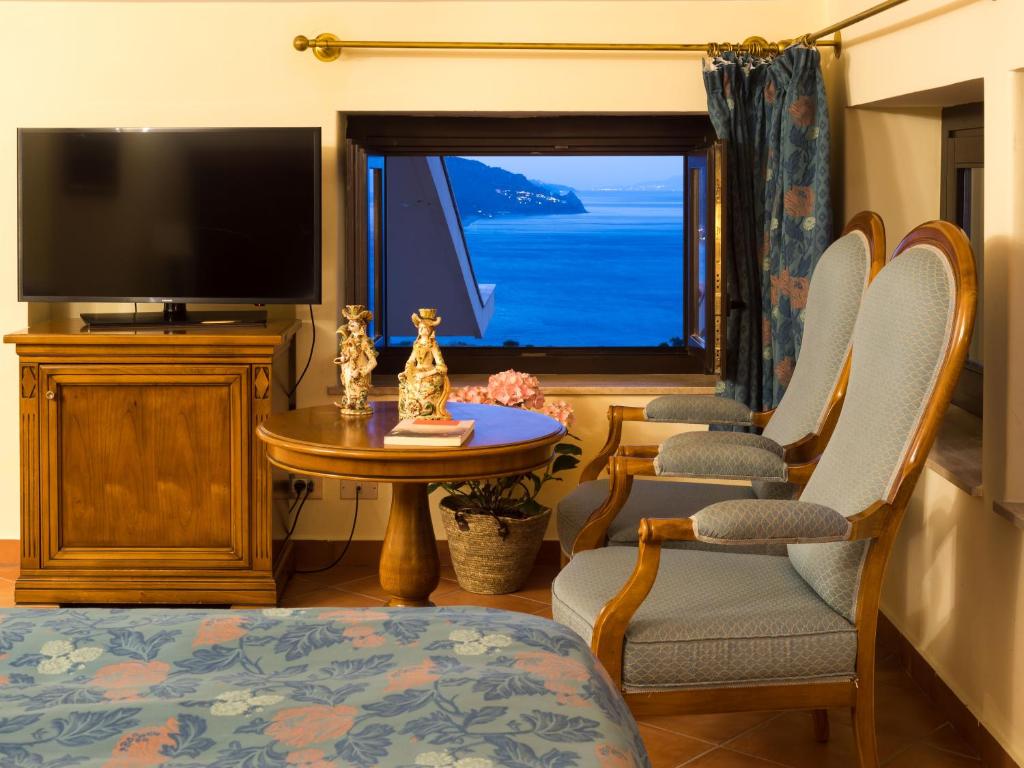 a living room with a tv and chairs and a table at Hotel Sirius in Taormina