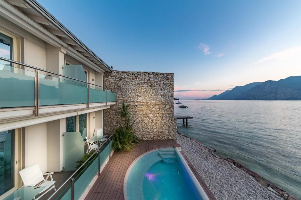 a balcony with a swimming pool next to the water at Hotel Vega in Malcesine