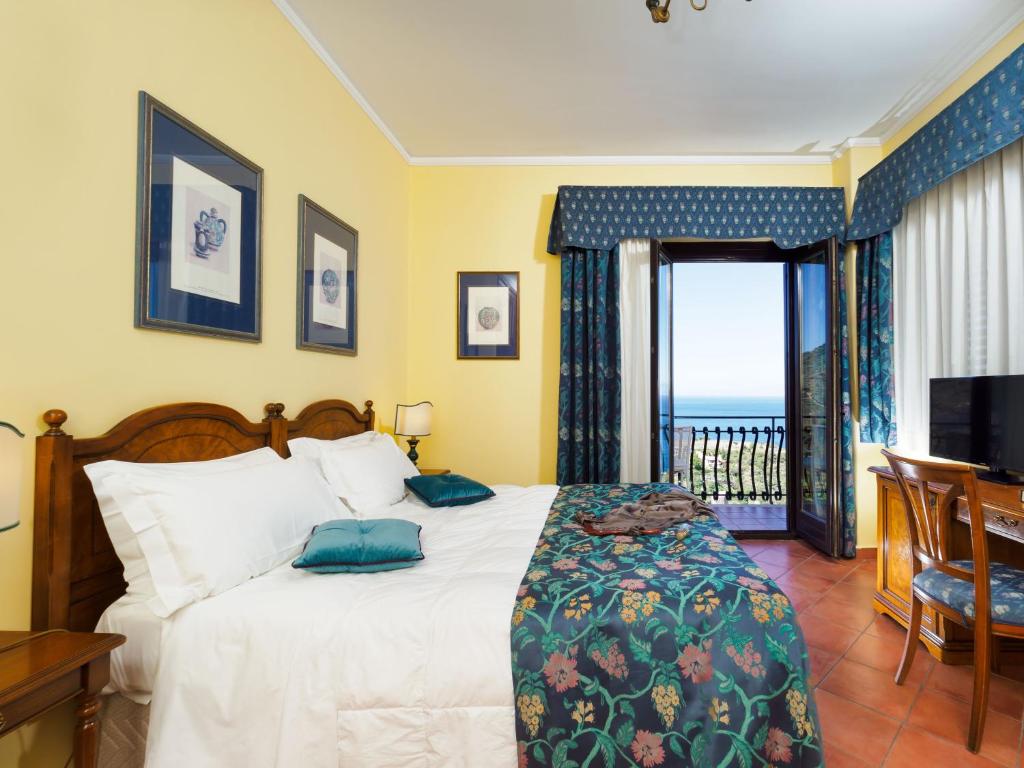 a bedroom with a bed with a view of the ocean at Hotel Sirius in Taormina