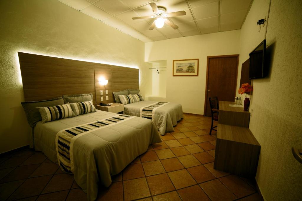 a hotel room with two beds and a television at Hotel La Mansion Suiza in Aguascalientes
