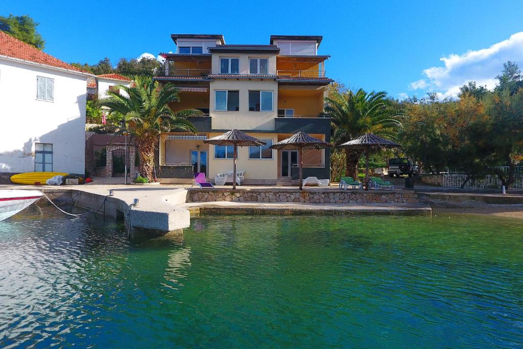 une maison sur l'eau devant un bâtiment dans l'établissement Apartments Savar - Ilo, à Brbinj