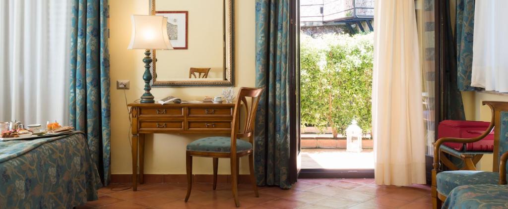 a bedroom with a desk and a chair next to a window at Hotel Sirius in Taormina