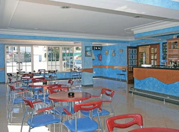 un restaurante con sillas y mesas rojas y paredes azules en Hotel Pipo, en A Lanzada