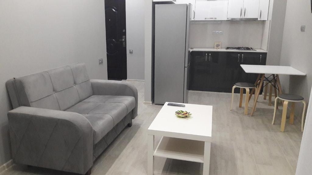 a living room with a couch and a table and a kitchen at E-Home Batumi in Batumi