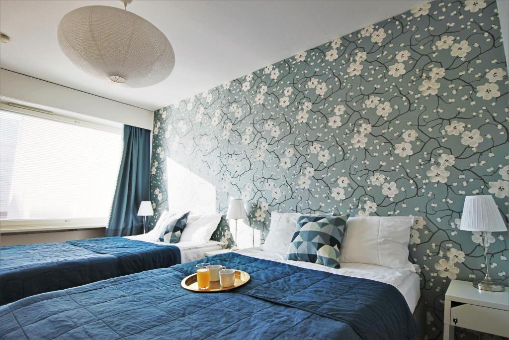ヘルシンキにあるStay Here Apartment Kamppiの花柄の壁紙を用いたベッドルーム1室(ベッド2台付)