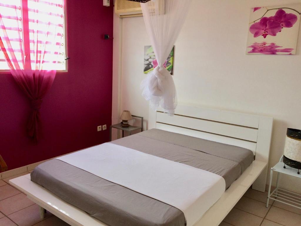 ein Schlafzimmer mit einem weißen Bett mit lila Wänden in der Unterkunft T2 à deux pas de la plage, résidence Anse Plage in Les Trois-Îlets