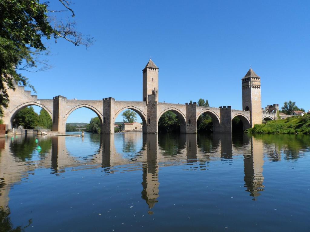 un puente sobre un río con su reflejo en el agua en Le Balcon des Jasses en Espère