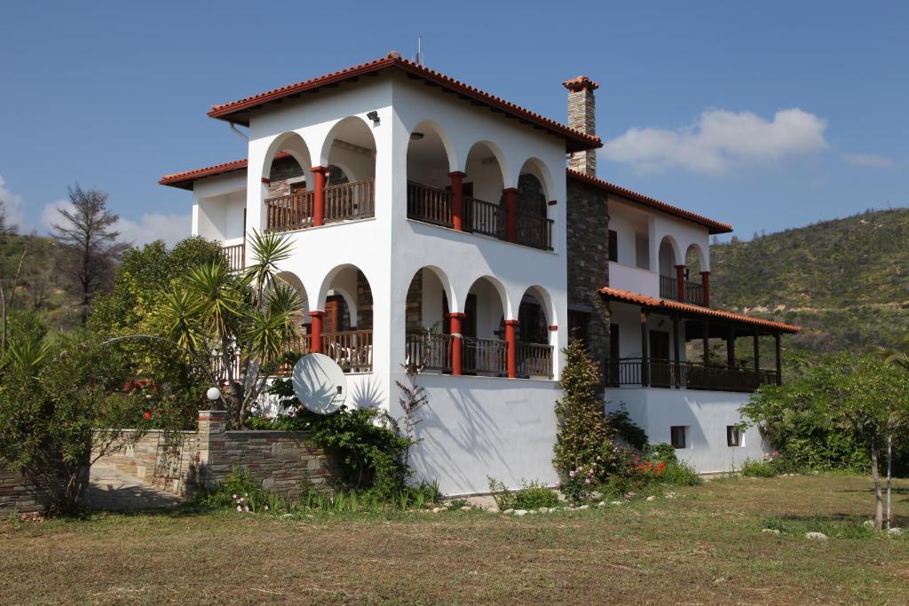 Villa Maria by RentalsPro - Ouranoupoli Halkidiki في أورانوبوليس: بيت ابيض كبير بأبواب حمراء وبلكونات