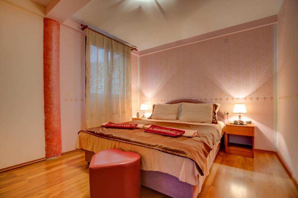 a bedroom with a large bed and a red stool at Sunny Villa Apartments in Budva