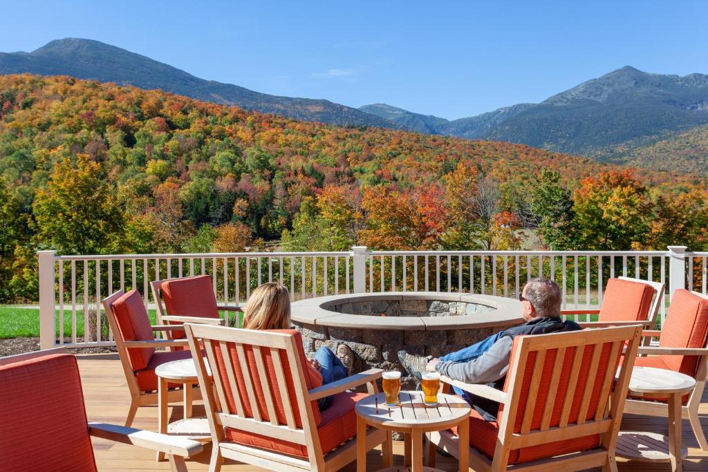 a man and woman sitting around a fire pit on a deck at The Glen House in Gorham