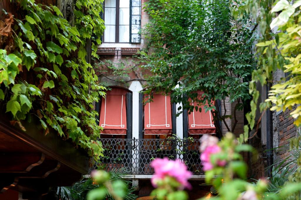 Un edificio con porte rosse e edera sopra. di Hotel Flora a Venezia