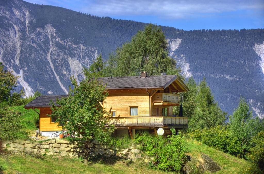 uma casa numa colina com montanhas ao fundo em Ferienhaus Oetztal em Sautens