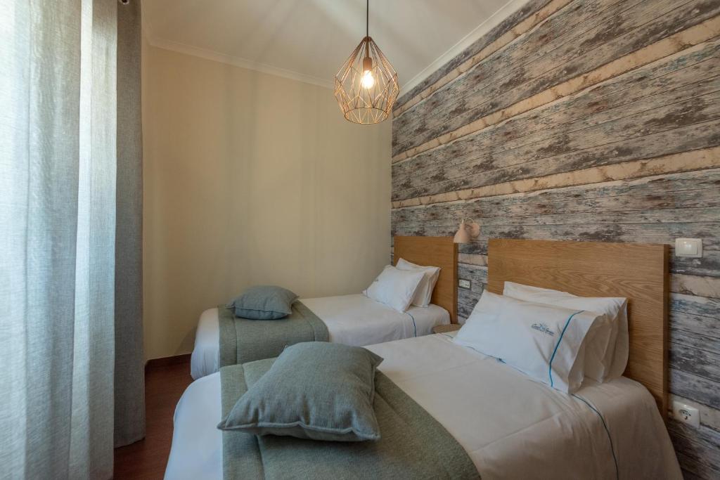 a bedroom with two beds and a wooden wall at Casa Poesia in Castanheira de Pêra