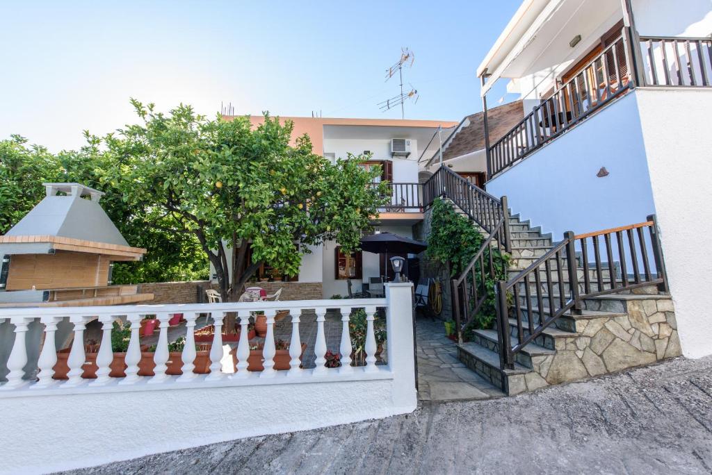 una casa blanca con escaleras y un árbol en Eleni Studios Neo Klima Skopelos, en Skopelos Town