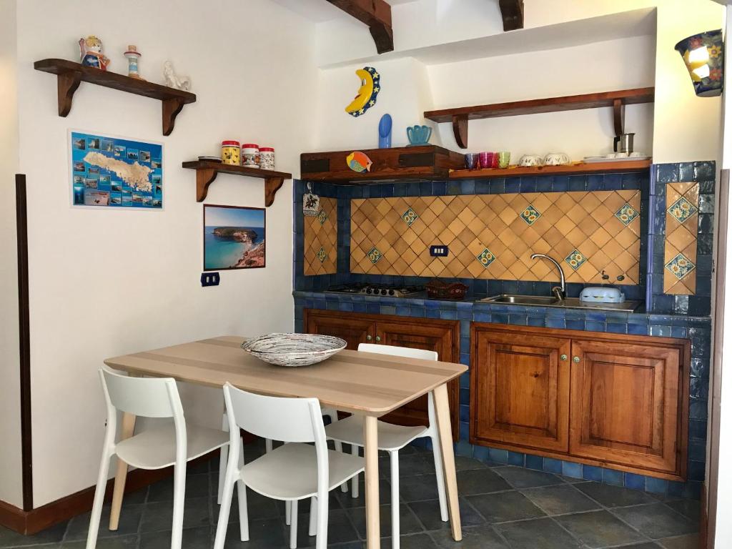 a kitchen with a wooden table and white chairs at Le case di Nunzia in Lampedusa