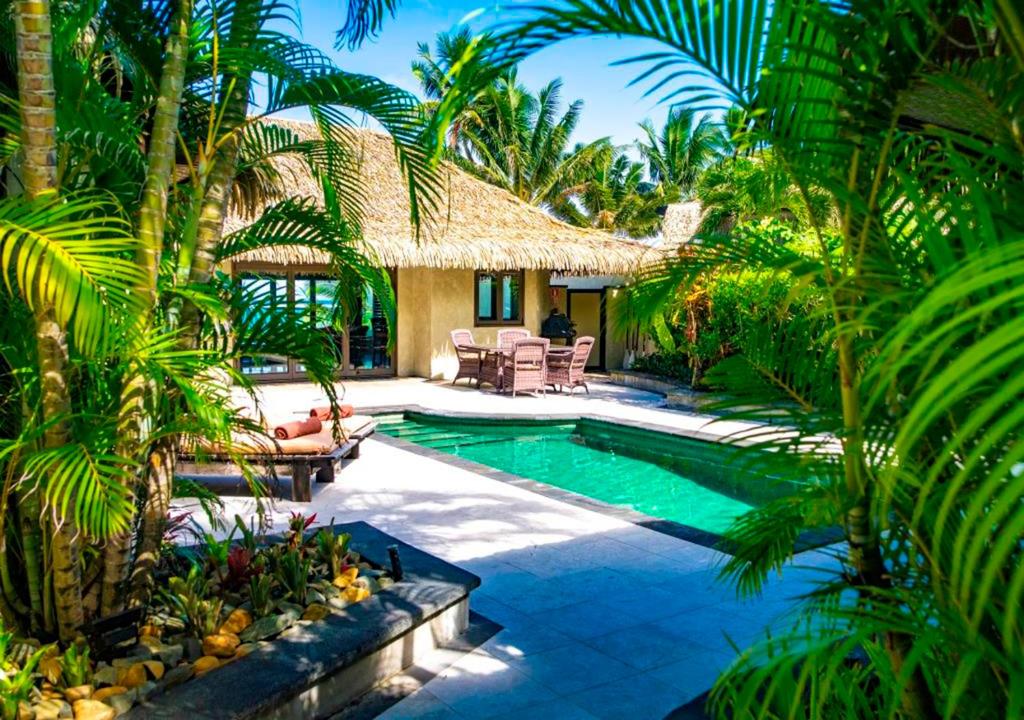 a swimming pool in a resort with palm trees at Te Manava Luxury Villas in Rarotonga