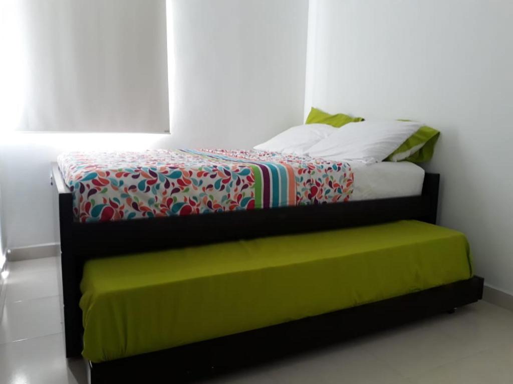 um quarto com uma cama com um banco verde ao lado de uma janela em APARTAMENTO AVENIDA CONDINA Primer Piso em Pereira