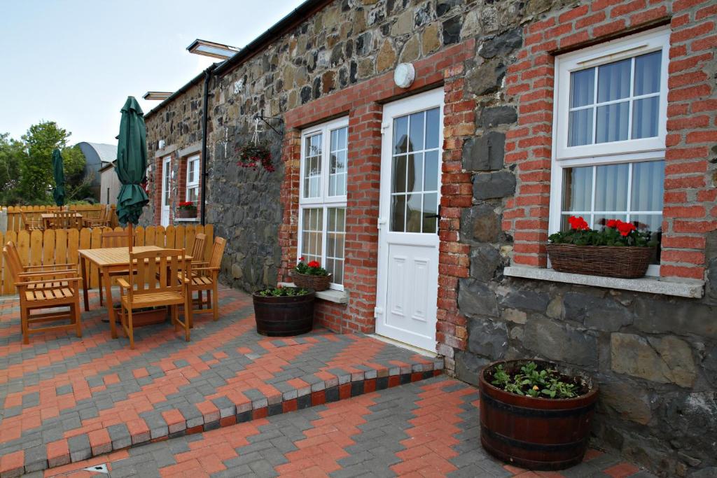 un edificio de ladrillo con un patio con mesa y sillas en Aunt Rachel's Cottage en Bushmills